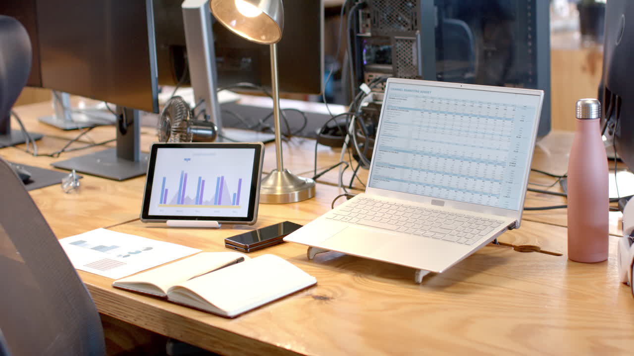 A modern business office setup showcases a laptop with data charts on the screen