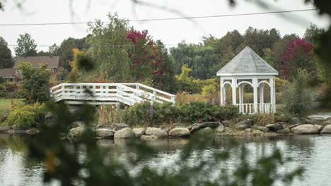 Wunderschöner-Pavillon-Auf-Einer-Insel-Inmitten-Eines-Gewässers-Mit-Einer-Weißen-Brücke,-Die-Zur-Insel-Führt