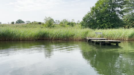 Peaceful-Water-Of-A-Lake-With-Grass-Reflections-In-Daytime