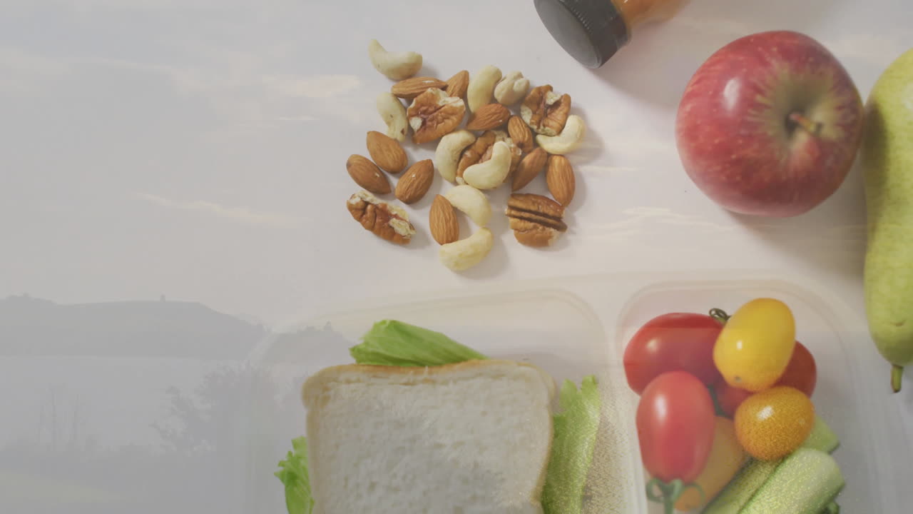 On table, colorful cherry tomatoes with apple, sandwich, nuts for healthy lunch