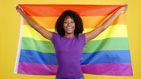 happy woman holding rainbow flag against yellow background