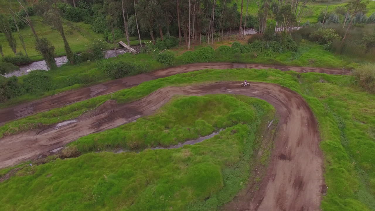 drone rastrea una moto de tierra alrededor de una pista de motocross junto al río