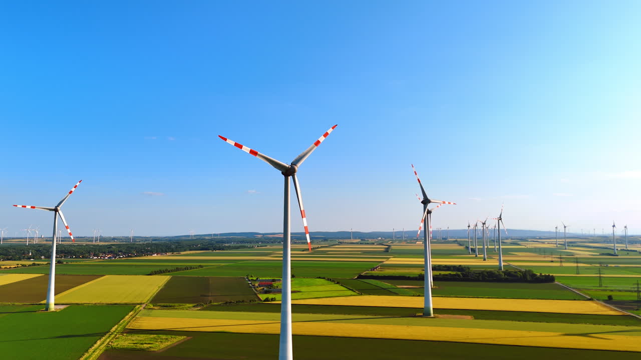 Wind turbines in a clear sky. Turbines spin gracefully in a vast, green landscape, reflecting renewable energy efforts in Europe during daytime