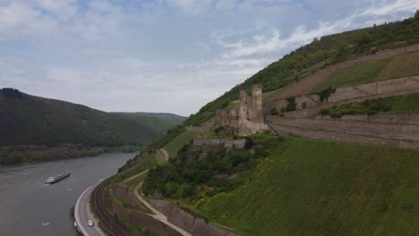 Industrial-ship-navigating-river-Rhine-beneath-Ehrenfels-Castle,-Germany