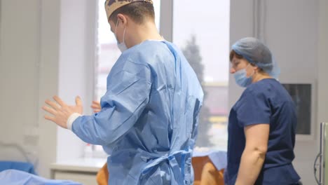 Surgeon Preparing for Surgery. The surgeon is preparing for the operation. A nurse helps a doctor put on a sterile suit