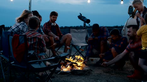 group of traveling friends frying sausages in campsite