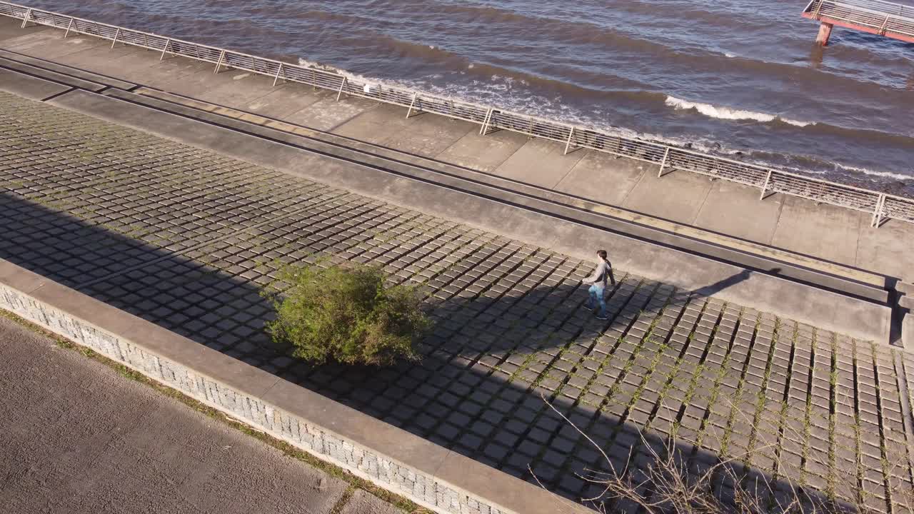 Nuori mies kävelee varovaisesti geometristen muotojen päällä maassa Buenos Airesin rantakadulla.