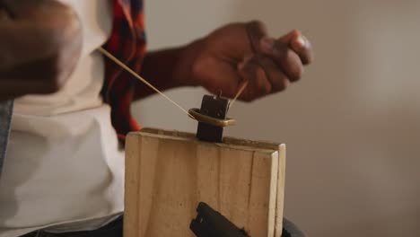 close up of hands of african american craftsman preparing belt in leather workshop