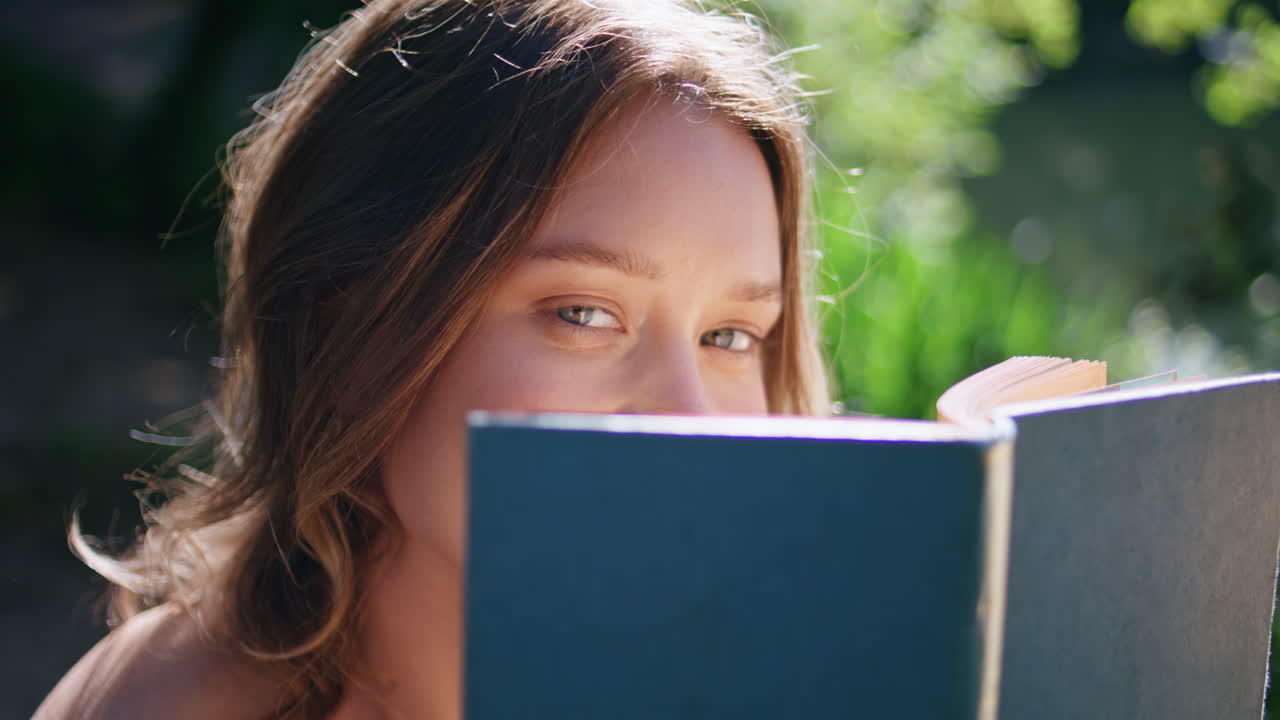 Gentle woman holding book sitting sunny nature portrait. Flirting model posing
