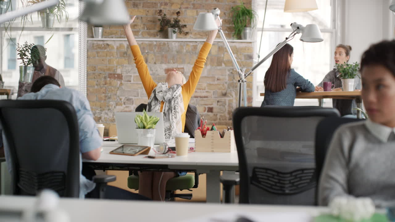 Business woman with arms raised celebrating success watching sport victory on laptop diverse people group clapping expressing excitement in office