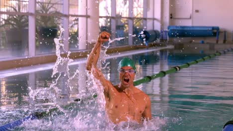 fit swimmer jumping up and cheering in the swimming pool