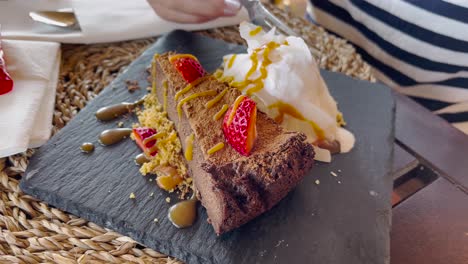 nahaufnahme von schokoladenkuchen mit schlagsahne und erdbeeren