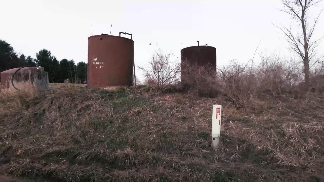 Slow motion driving past an Oil collection tank on a farm.