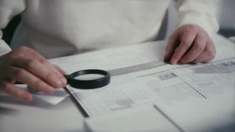 arquitecto o ingeniero revisando con una lupa las medidas de los planos de cimentación de una casa