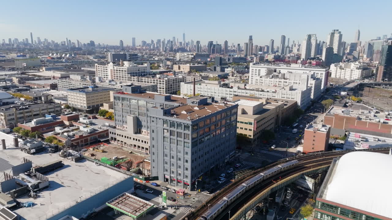 Panoramic drone shot of a train passing modern condos in Brooklyn, sunny NY