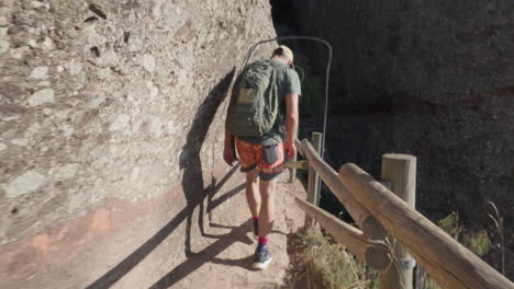 brave expedition: man treads hazardous trail alongside tall rocky cliff