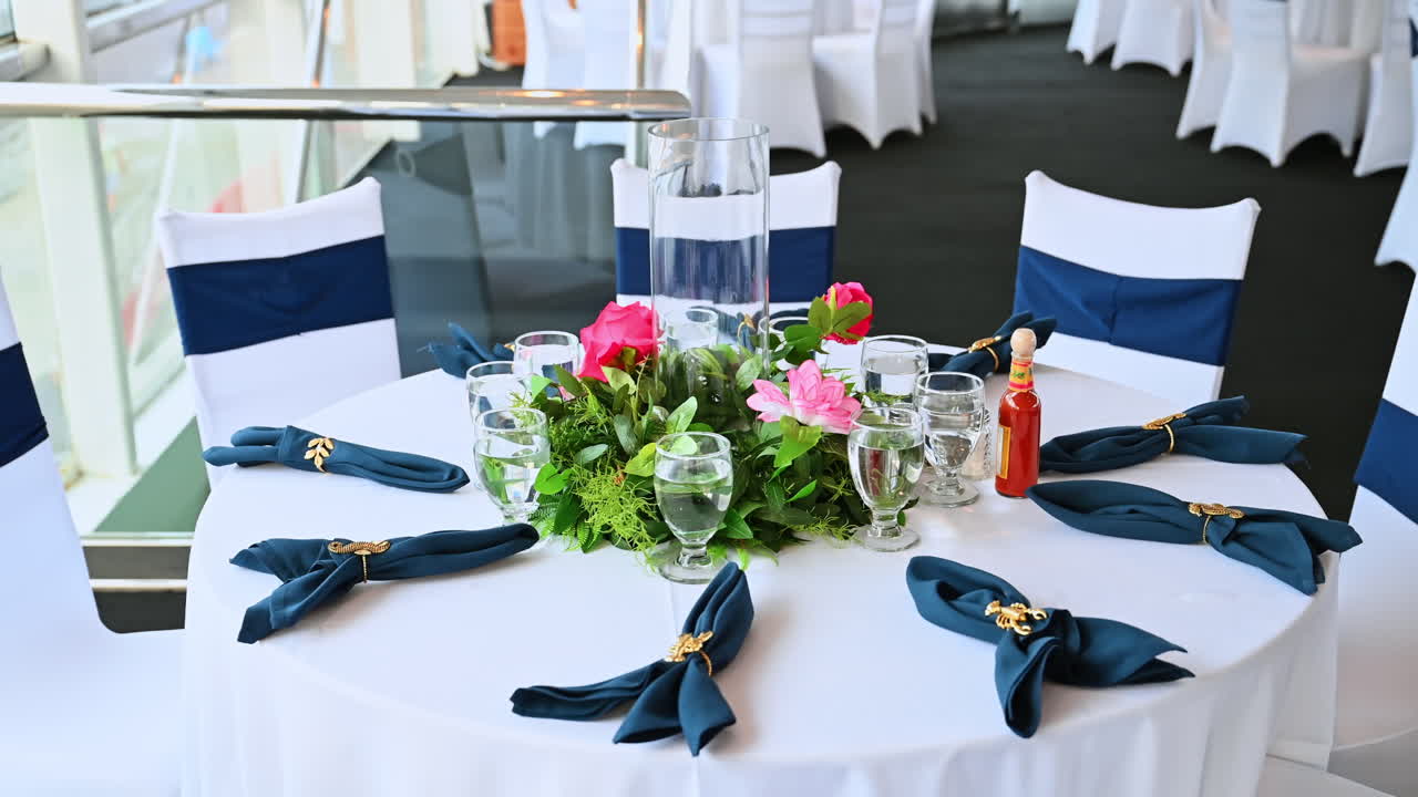 Elegant, rundt spisebord plassert på et cruiseskip. Vakkert dekorert, rundt bord med hvit duk, blå servietter og blomstermidtstykke i cruiseskipets spisesal