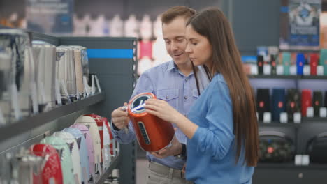 young couple man and woman in appliances store chooses an electric kettle on the counter