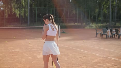 a young woman practicing tennis on an outdoor court with a coach. the coach provides guidance as the player works on her technique, perfecting her strokes in an athletic training session.