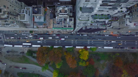 Aerial-birds-eye-overhead-top-down-panning-shot-of-traffic-on-street-leading-along-park.-Autumn-colour-trees-in-Central-park.-Manhattan,-New-York-City,-USA