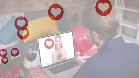 múltiples iconos de corazón rojo flotando sobre el hombre caucásico agitando mientras tiene una videollamada en la computadora portátil