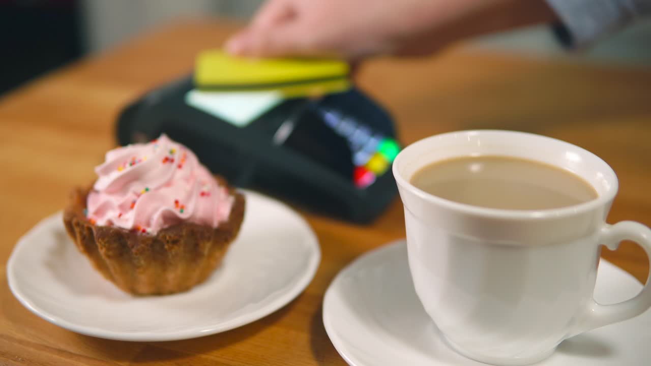 Coffee and pastry with payment terminal on wooden table