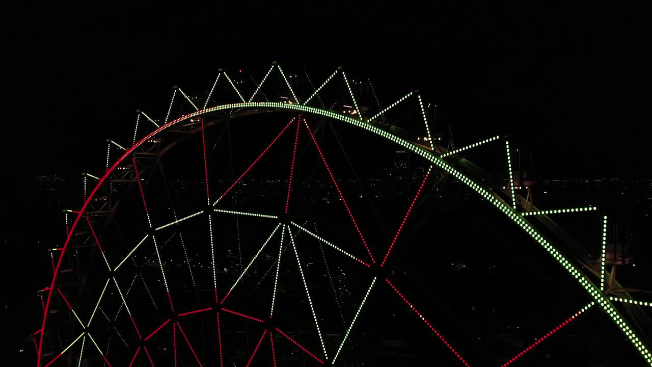 Aerial close-up: Ferris wheel at Aztlan Parque Urbano with Mexico City&acute;s skyline as background at night