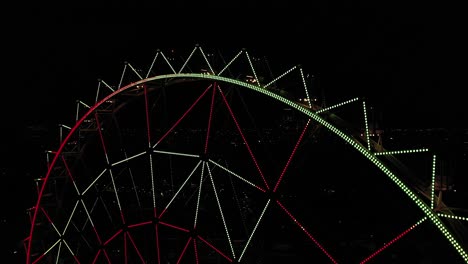 aerial close-up: ferris wheel at aztlan parque urbano with mexico city´s skyline as background at night