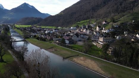 clip de drone de un río tranquilo junto a un pueblo suizo tradicional en los alpes