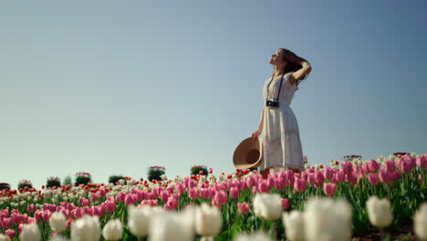 Camera-moving-around-girl-staying-in-tulip-field.-Woman-enjoying-summer-day.