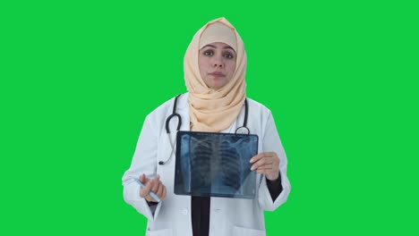 estresado médico musulmán comprobando el informe de rayos x al paciente pantalla verde