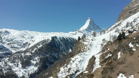 Aerial-of-snow-covered-mountain-edge-overlooking-large-valley