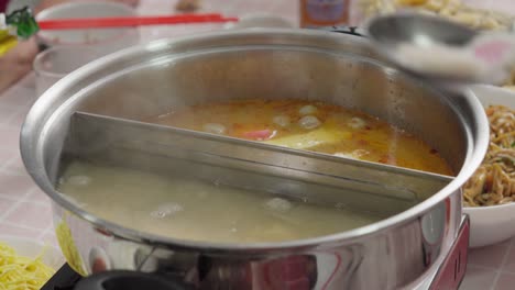 Thai-Tom-yum-boiling-soup-and-collagen-soup-split-in-a-silver-soup-pan