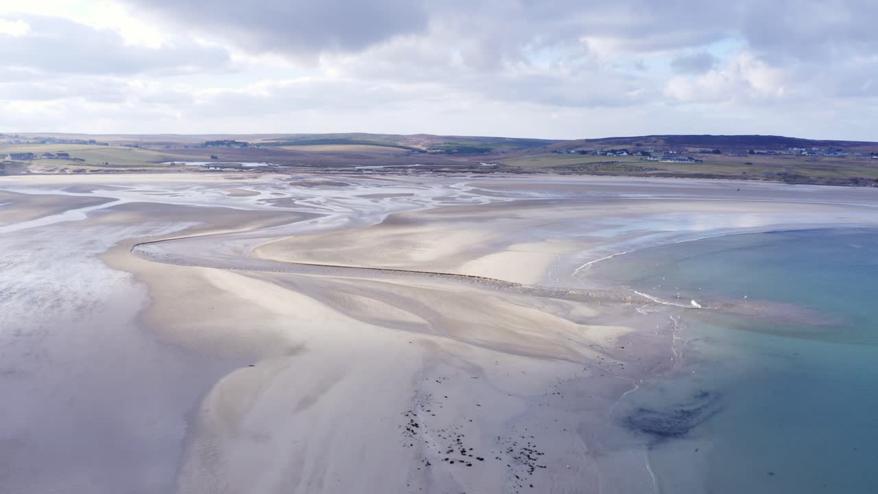 toma de un dron de un río que se encuentra con el mar en la playa de gress durante la marea baja en las hébridas exteriores de escocia