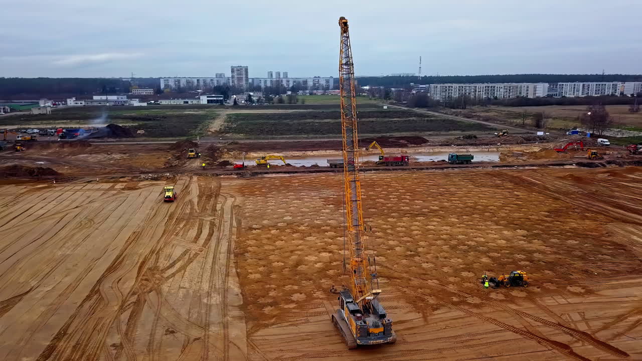 una grúa que deja caer un peso en un sitio de construcción para la compactación dinámica del suelo - vista aérea