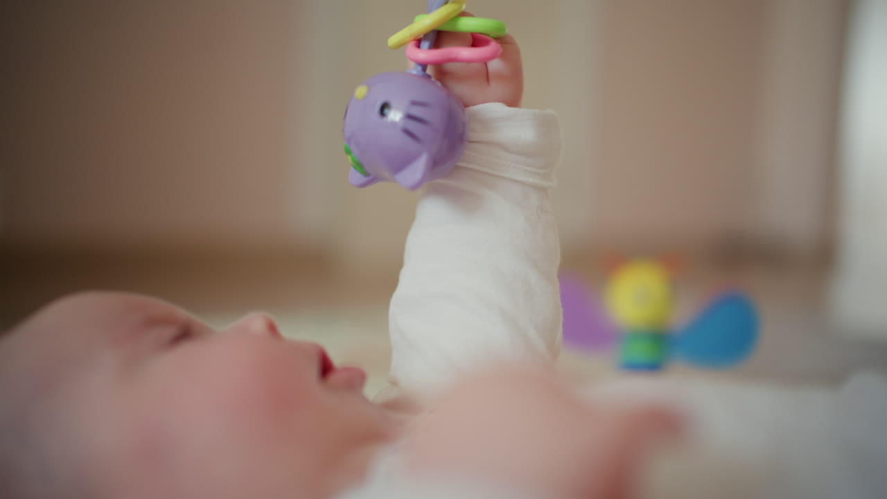 Close up of baby holding a colorful rattle toy