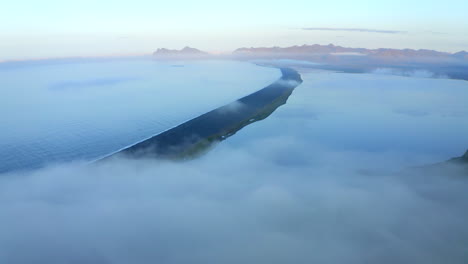 Drone-aerial-footage-of-Hvalnes-Nature-Reserve-Beach-with-cloud-inversion-beach-surrounded-by-sea-in-Southern-Iceland