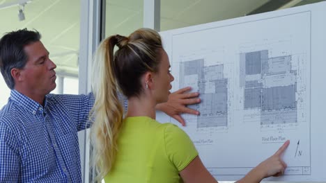 Caucasian-male-and-female-architects-discussing-over-blueprint-in-the-office-4k