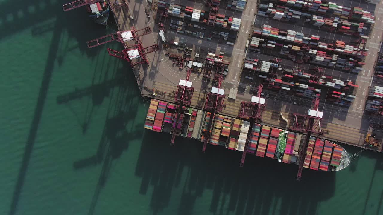 gran barco de contenedores atracado en el puerto comercial de hong kong, vista aérea de arriba hacia abajo que incluye pilas de contenedores de envío en una plataforma de espera