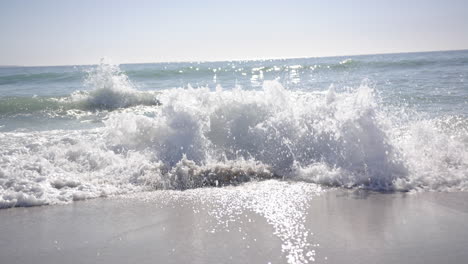 foamy waves crash onto the sandy shore under a clear sky with copy space