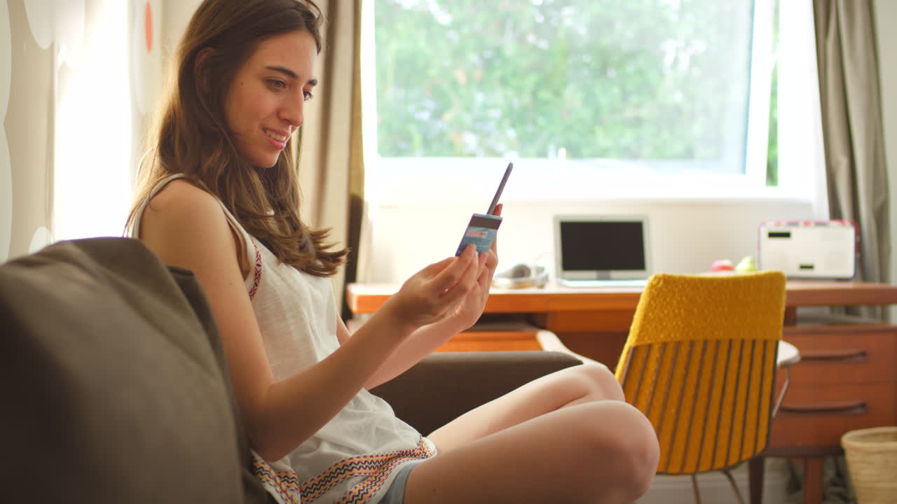 집에서 스마트폰과 신용카드를 사용하는 젊은 여성