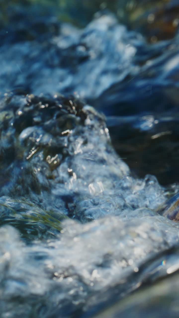 Primo piano di acqua cristallina che scorre e schizza sulle rocce