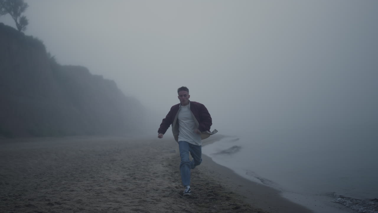 Casual guy running sandy beach in morning. Young man moving fast along sea shore