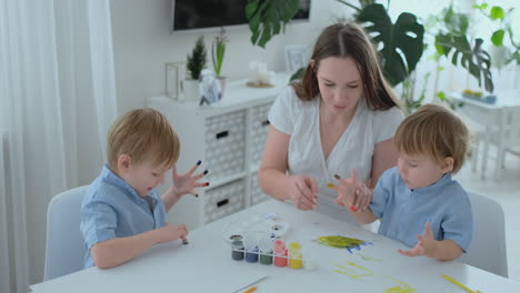 dos hijos de varones y una madre se dedican al desarrollo creativo haciendo tareas con los dedos en el papel. el desarrollo de las sensaciones táctiles y las matemáticas pequeñas.