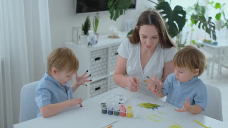 two children of boys and mother are engaged in creative development doing homework by fingering on paper. the development of tactile sensations and small mathematics.