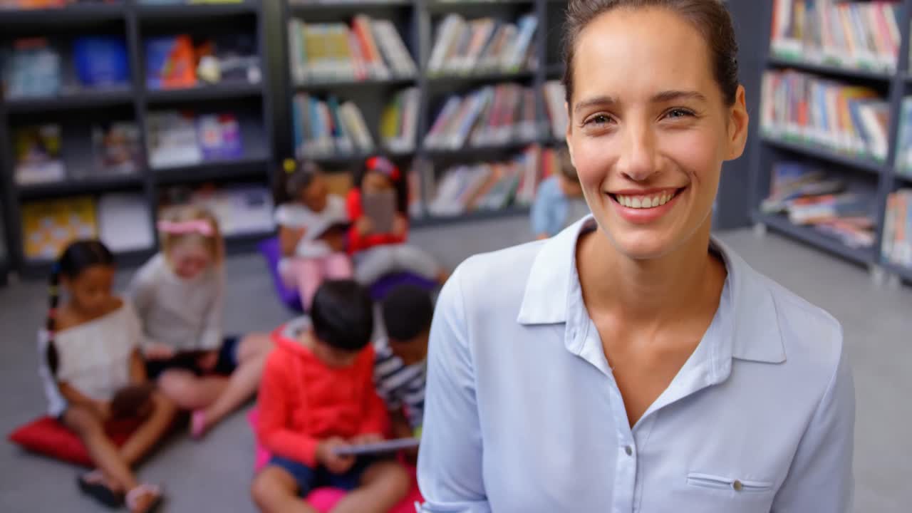 vista frontal de una feliz maestra caucásica de pie en la biblioteca de la escuela 4k