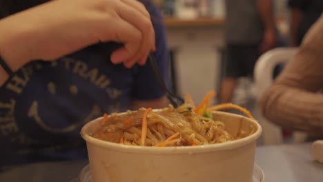 person eating hot noodles in a market