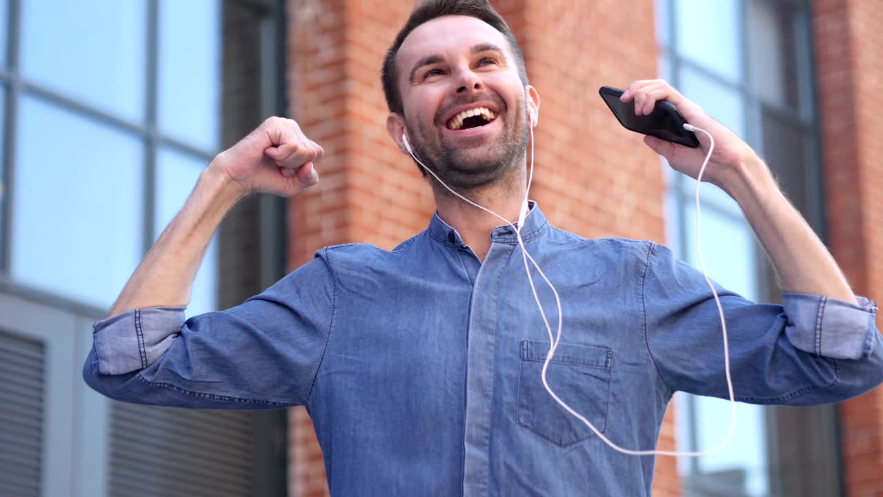 hombre feliz bailando escuchando música en su teléfono inteligente