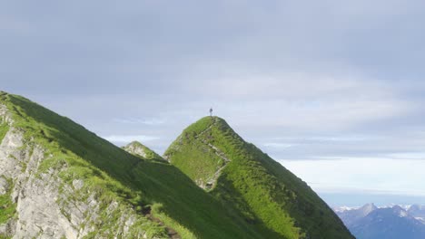 turysta na szczycie zielonego szczytu górskiego, ciesząc się panoramicznymi widokami