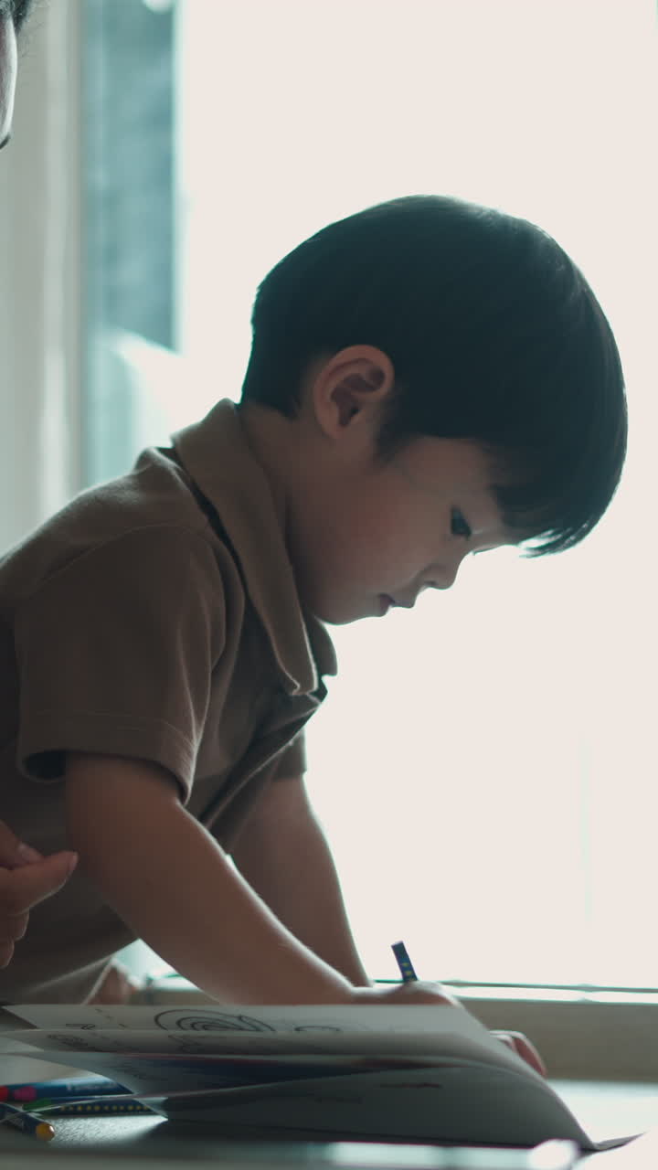 Bambino che disegna e colora con pastelli in casa